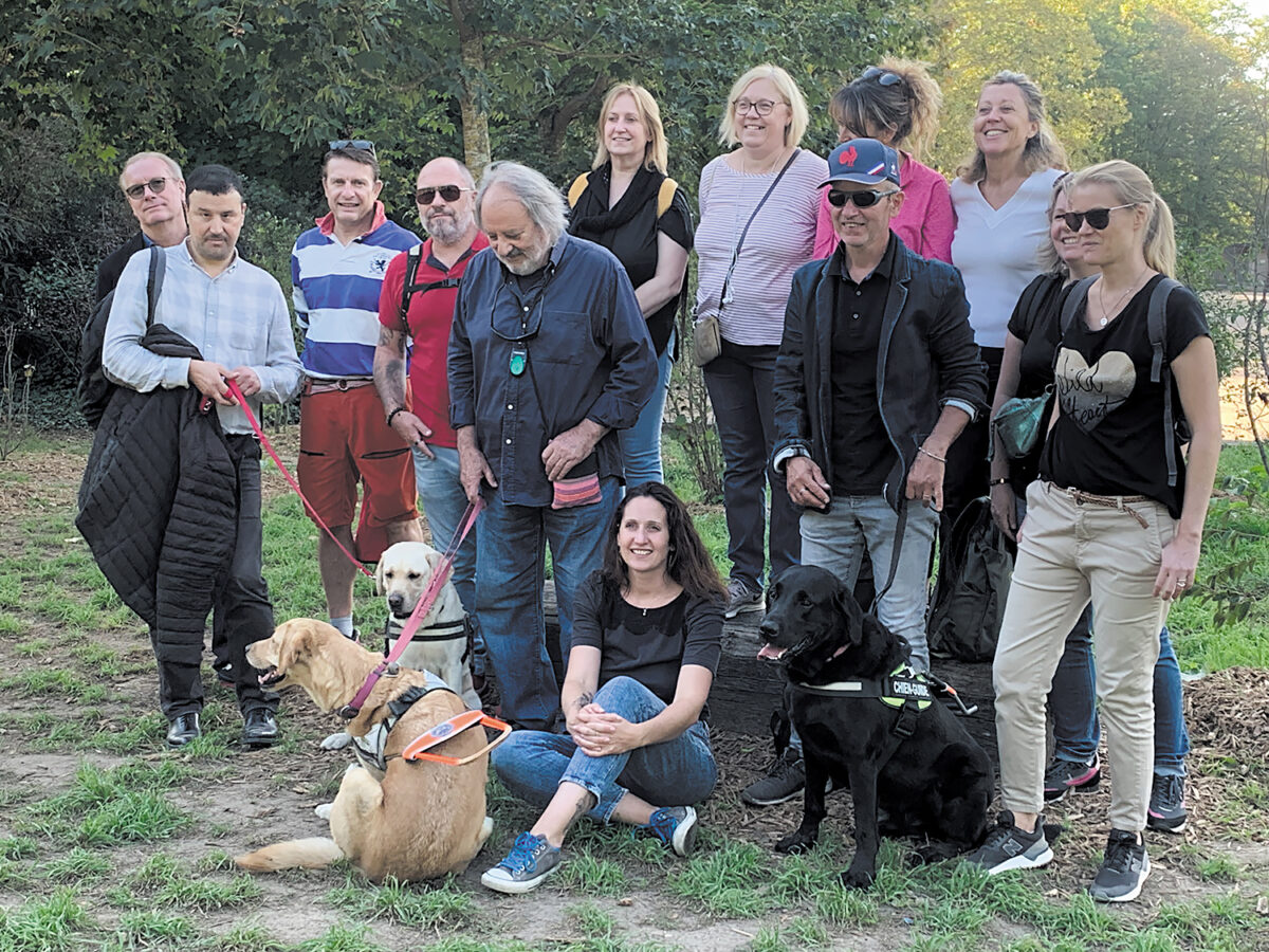 Au parc de la Tête d'Or à Lyon, Hichem Houma, Mario Eljerrat et Régis Ducruix posent, accompagnés de leurs chiens Romie, Ottawa et Népal, entourés d'une dizaine de salariés des laboratoires Boerhinger-Ingelheim.